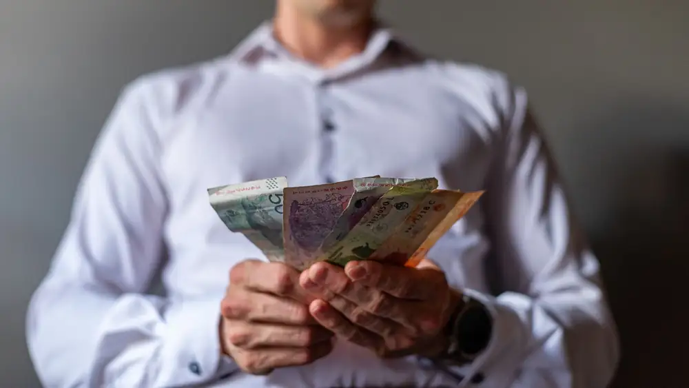 Man holding Argentine Peso banknotes in Buenos Aires, Argentina, illustrating currency concept.