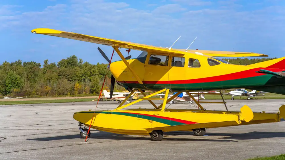 Bright yellow seaplane stationed outdoors at Stratford Airport in Ontario, Canada under clear blue skies.
