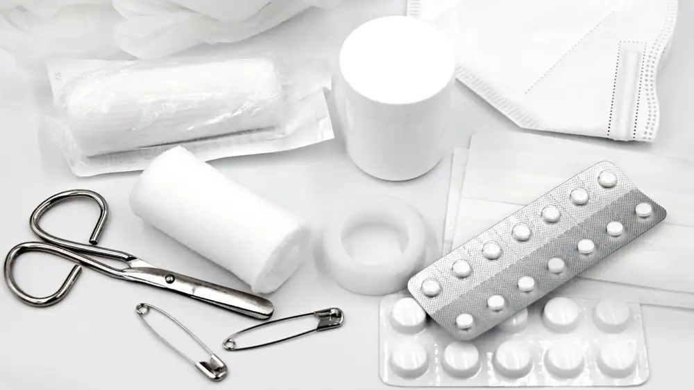 A flat lay of essential first aid supplies and medical equipment on a white background.