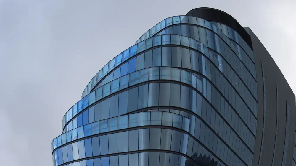 Glass facade of a futuristic skyscraper in Melbourne, reflecting urban architecture.