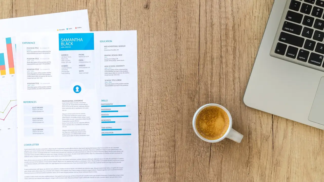 Top view of a desk with resume, coffee cup, and laptop on a wooden surface, ideal for business concepts.