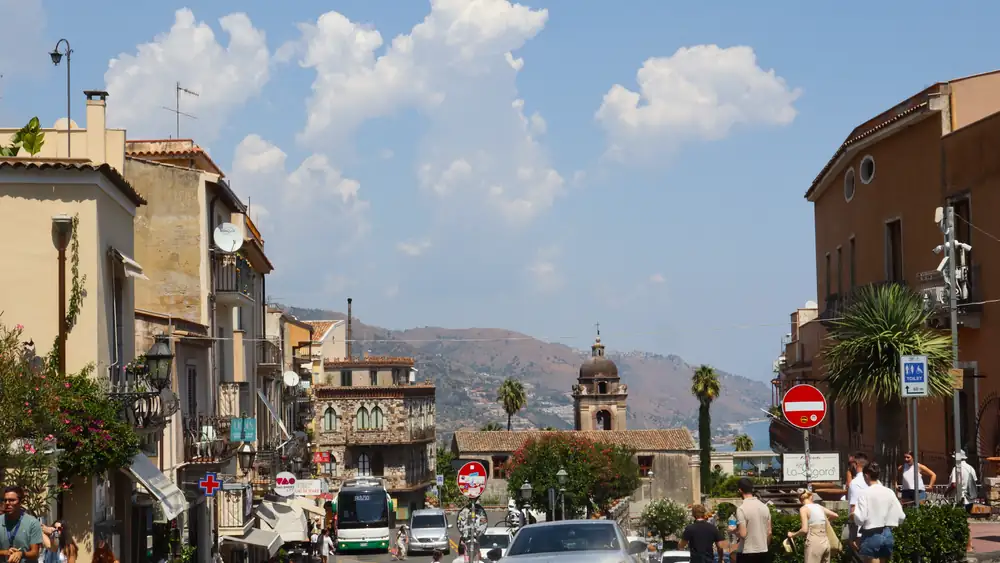 Tourists enjoy a sunny day exploring the vibrant streets of Taormina, Sicily, Italy.