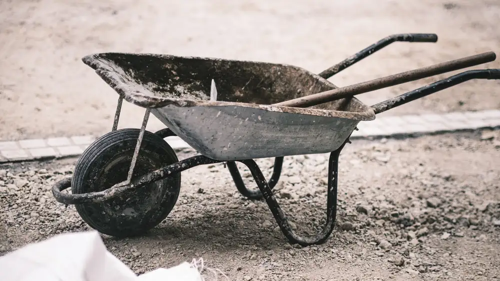 An old wheelbarrow on a gravel construction site, highlighting rustic work tools.